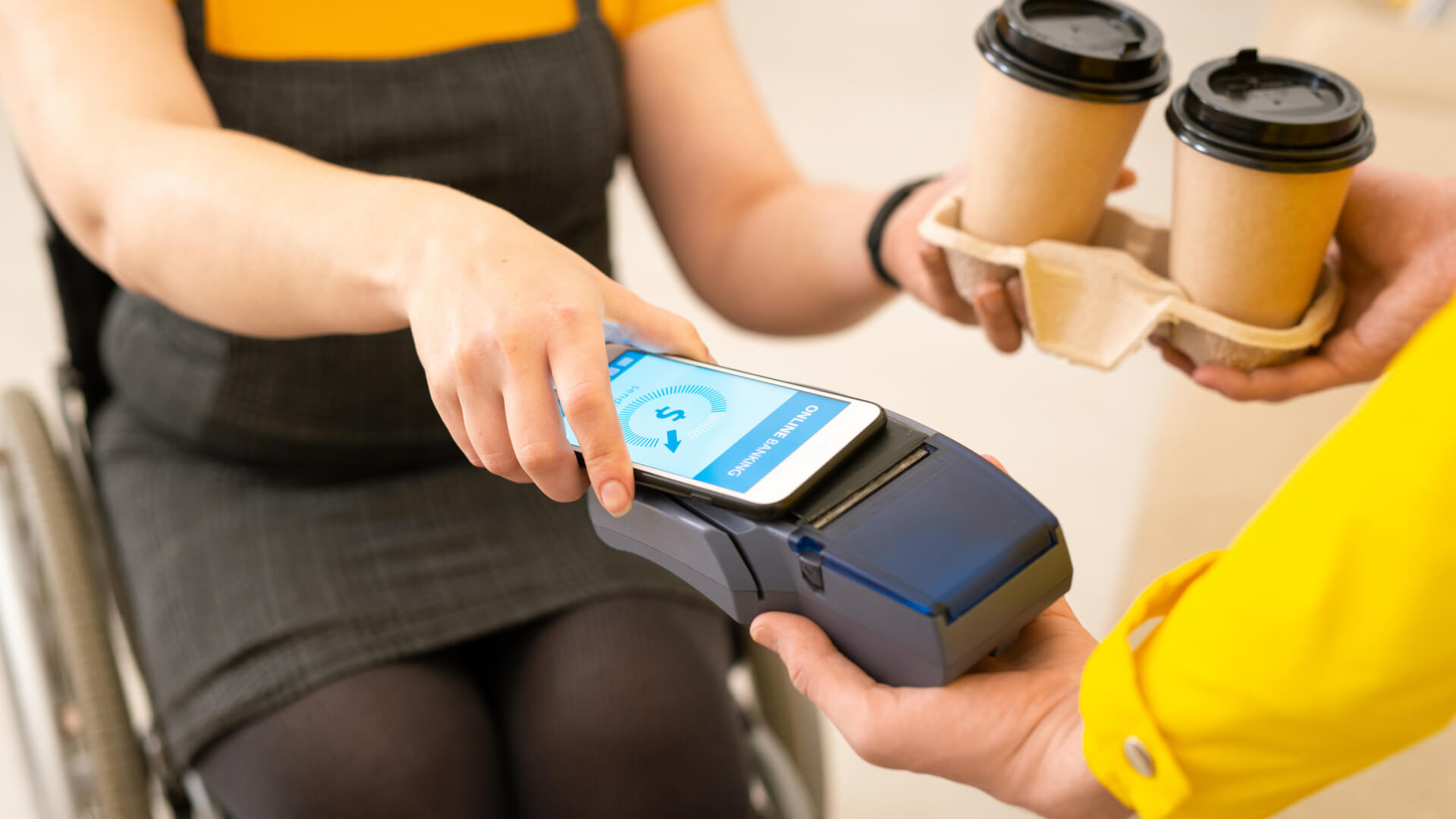 young-disable-woman-casualwear-sitting-wheelchair-holding-smartphone-payment-machine-while-paying-ordered-coffee
